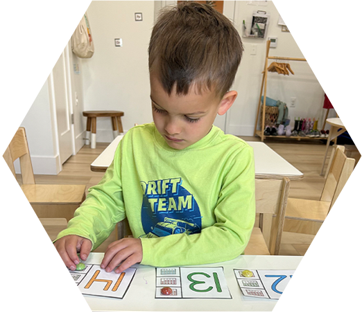 Pre-K student practicing number recognition with hands-on counting and number cards.